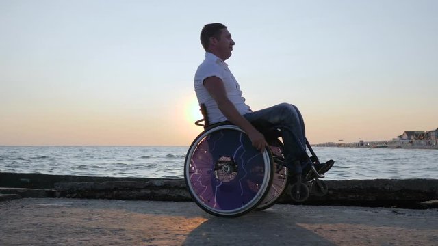 disabled person sitting in wheelchair at embankment, cheerful handicapped man on invalid carriage