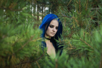 Naklejka premium Beautiful woman with dark blue hair dressed in black dress in the magic forest