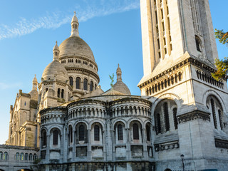 Three-quarters rear view of the dome of the Basilica of the Sacred Heart of Paris at sunrise with the square steeple in the foreground.