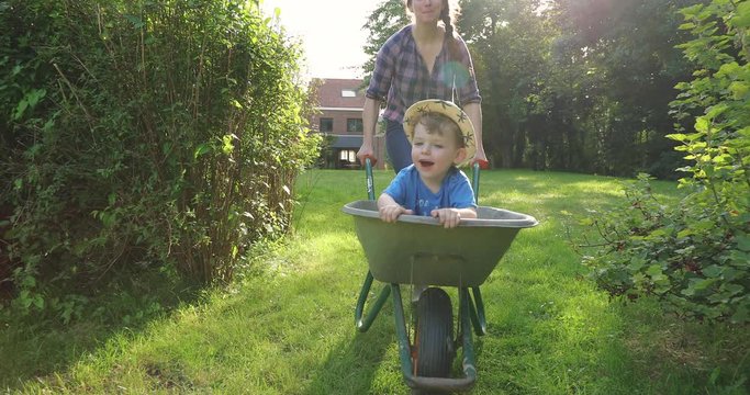 Little boy having a ride in a wheel barrow slow motion