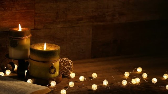 This is a close-up video symbolizing the Christmas holiday season, using a Bible setting with candles inside a barn background made up of old red wood.