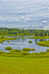 Fototapeta na wymiar Travel Concepts and Ideas. Belarussian National Park Braslav Lakes Surrounded by Densely Forested Area at Noon During Summertime.