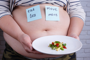 Two simple ways to be fit. Overweight fat woman with stickers on her belly "Eat less" and "Move more" holding a plate with little portion of food. Restraint, diet, nutrition, overweight, weight losing