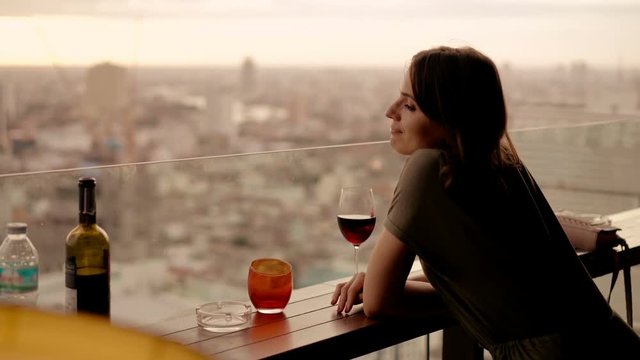 Woman listening music and dancing in rooft bar in the city, 4K
