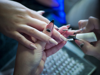 Woman in a nail salon receiving a manicure by a beautician with nail file woman