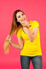 Funky young woman in yellow  t shirt pose over pink background