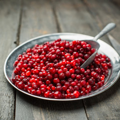 Christmas card. Frozen Red cranberries in the iron plate on a wooden background. Winter postcard. Place for your text and greetings