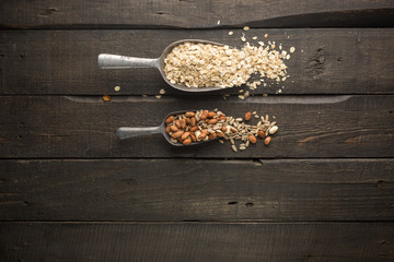 Natural products in iron vintage scoops on wooden granary boards. Hercules flakes (oat flakes), sunflower seeds, fresh peanuts, hazelnuts, honey. Ingredients for granola or oatmeal. Useful breakfast.