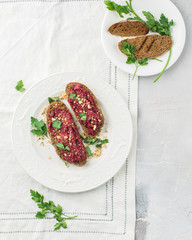 Homemade toast from whole grain bread with beet paste, greens and nuts. Light concrete background, white soft. Place for text. Food photo with hands. Useful dietary baking. Flat lay, top view