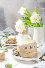 Obraz na płótnie Canvas Traditional Easter cake on a light wooden background. Decorated with flowers. Next to a small cake, quail eggs and flowers. Cut a piece of cake. Easter. Celebration. Spring. Rustic style