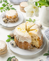 Traditional Easter cake on a light wooden background. Decorated with flowers. Next to a small cake, quail eggs and flowers. Cut a piece of cake. Easter. Celebration. Spring. Rustic style