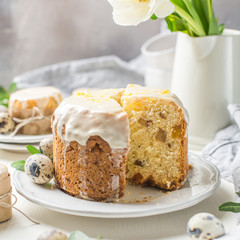 Traditional Easter cake on a light wooden background. Decorated with flowers. Next to a small cake, quail eggs and flowers. Cut a piece of cake. Easter. Celebration. Spring. Rustic style