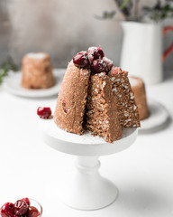 Chocolate mini raw cake with cherry and cottage cheese, decorated with cherries and coconut. Traditional Russian Easter dessert. On a light white wooden background. Piece of cake.