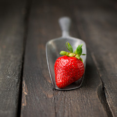 Fresh strawberries on a wooden vintage background with a vintage iron scoop. Place for text