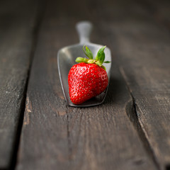 Fresh strawberries on a wooden vintage background with a vintage iron scoop. Place for text