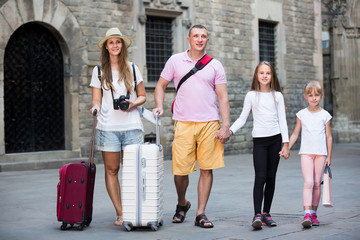 Fototapeta premium Cheerful family walking with suitcases