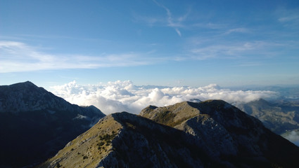The mountain Lovcen in Montenegro. Capped mountains and fluffy white clouds below the peaks