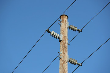 Powerlines at an electric wooden pole against blue skies