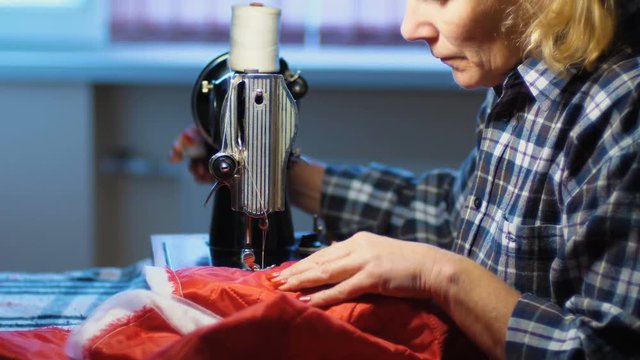 Woman sews on old sewing machine at home