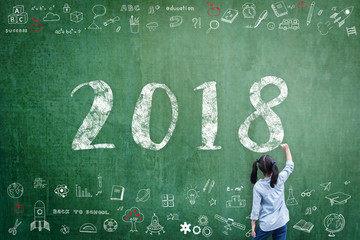 2018 new calendar year greeting by kid's hand drawing on school teacher's chalkboard with student's...