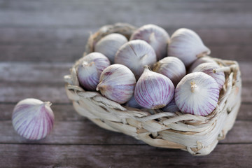 Small garlic in a basket on a wooden background