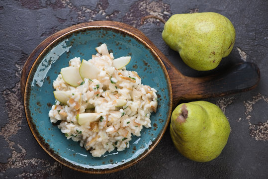 Turquoise plate with pear risotto on a brown stone background, top view, studio shot