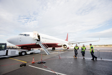 Crew Leaning On Fence While Standing By Airplane