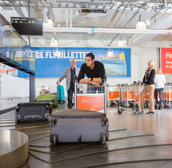 Man Waiting For Baggage From Conveyor Belt At Airport