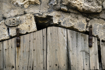 wooden door entrance with metal features. wooden door with door number 13. rusty thirteen number label. stone building with plank door.