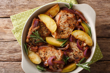 Spicy baked pork chop with green apples, onion and rosemary close-up in a baking dish. horizontal...