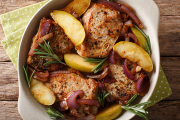 baked pork with green apples, onions and rosemary close-up. horizontal top view