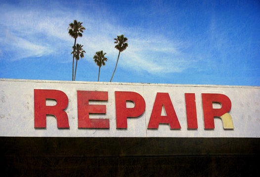 aged and worn repair sign with palm trees