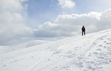 Fototapeta na wymiar Man hiking up the snow-covered slope in Carpathian, Ukraine.