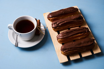 Cup of hot tea with cinnamon steak and french chocolate eclairs