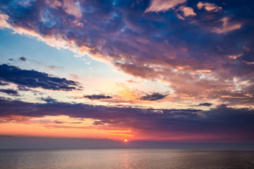 Naklejka na ściany i meble Sunset over calm sea in summer with sun beam