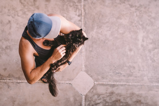 Young male adult carrying cute cat on his arms