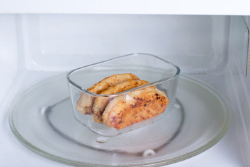 Container with food in the microwave. Cutlets in a container