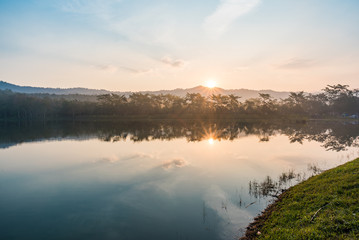 sunrise scene with mountains, trees and pond