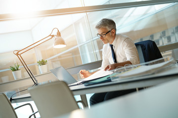 Businessman in office working at desk on laptop computer