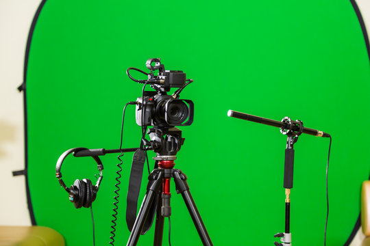 Video camera on a tripod, headphones and a directional microphone on a green background. The chroma key. Green screen.