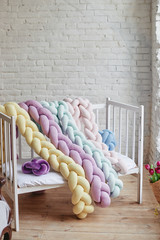 Baby room: bed on white brick background. Colorful braided cribs