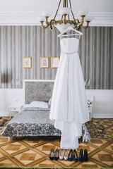 Peg with white wedding dress hangs on the chandelier