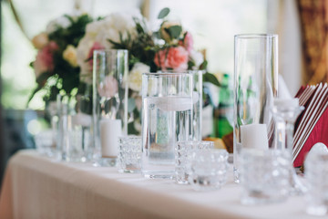 Vases with white candles stand on a dinner table