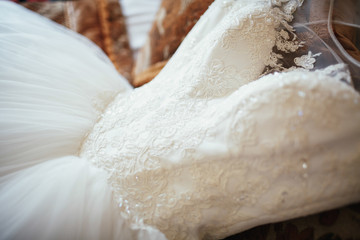 Rich wedding dress lies on the bed in luxurious room