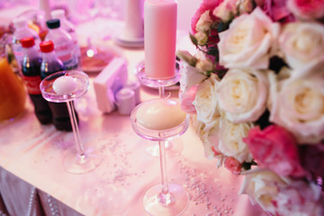 Little white candles stand on pink dinner table