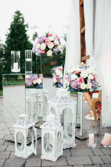 Glass boxes with flowers and white lanterns stand before wedding altar outside