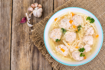 Soup with meatballs for dinner on wooden background