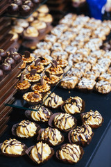 Wooden and black dishes with different kinds of desserts served on a black table