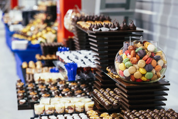 Wooden and black dishes with different kinds of desserts served on a black table