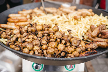 Large frying pans with vegetables stand on gas outside